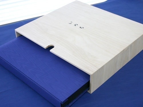 展示用台紙とポケット御城印帳のピジョン株式会社による遺影アルバムのページ。遺影アルバムの特長2.桐材で出来た木製ボックス付き。の画像はこちらです。